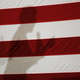 Elizabeth Warren’s shadow on a flag at Roosevelt High School in Des Moines, Iowa, in October 2019.